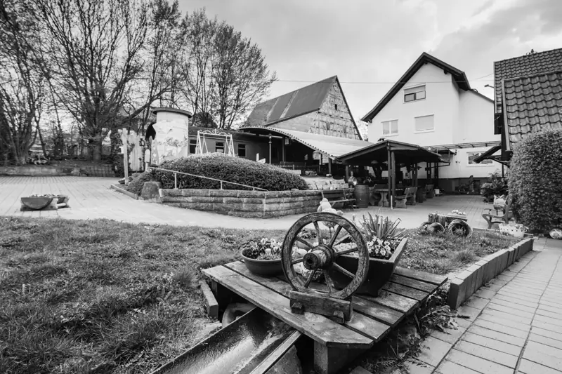 Schwarzweißaufnahme des Außenbereichs mit Wagenrad